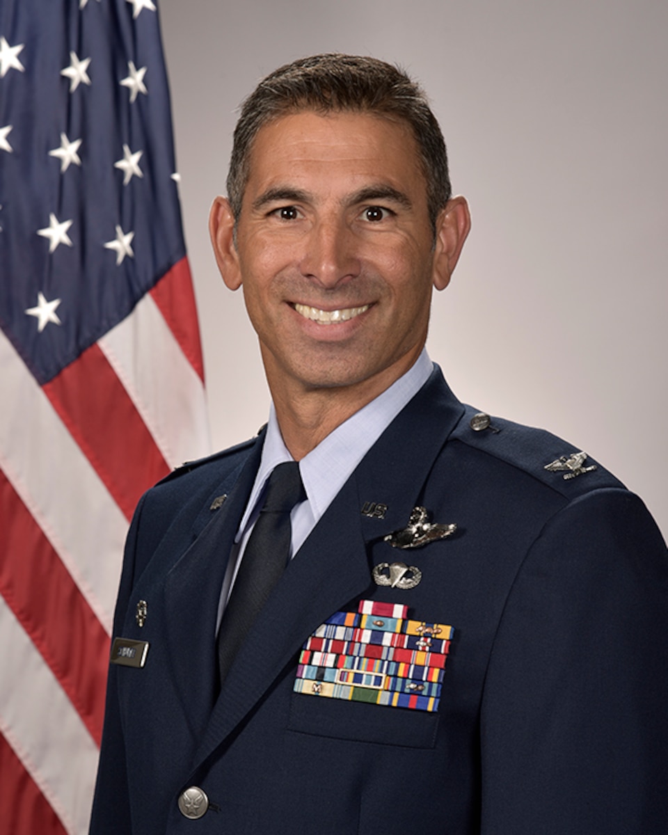 A portrait of a man in Air Force service dress with the American flag in the background.