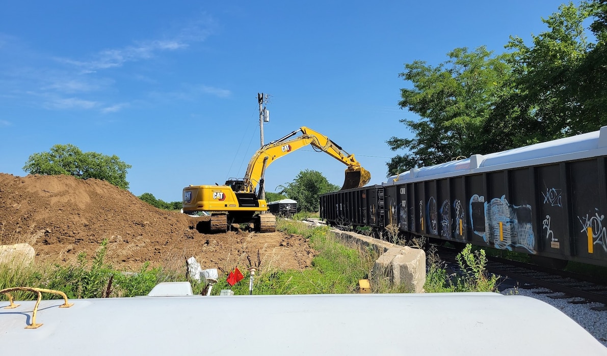 An excavator operator, Jake Burgus, loads the first railcar during a recent Transportation and Disposal (T&D) campaign from the Formerly Utilized Sites Remedial Action Program (FUSRAP) at the Iowa Army Ammunition Plant (IAAAP) near Middletown, Iowa, Tuesday, July 18, 2023. By the time Cabrera Services had completed the load-out Sunday, July 23, 2023, the FUSRAP team had filled 23 railcars with approximately 2,428 tons of depleted uranium (DU)-contaminated soil that was above the remediation goal. The team dispatched the railcars to U.S. Ecology-Michigan, a licensed, out-of-state disposal facility.