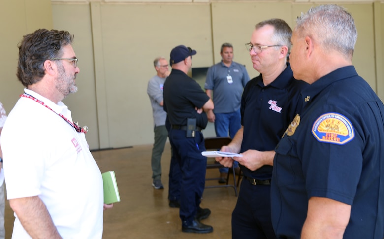 Two men on the right side of the image are speaking with another man on the left side of the image