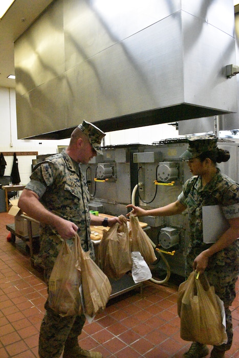 Customer, Staff Sgt. Maxwell Lewis accepts bagged grocery items from Cpl. Sophia Marie Ramos.