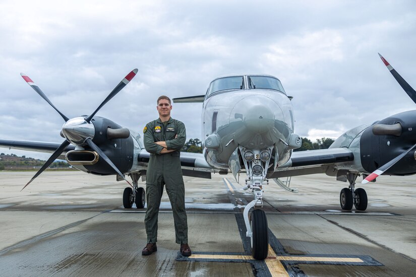 A Marine poses for a photo in front of a parked aircraft.