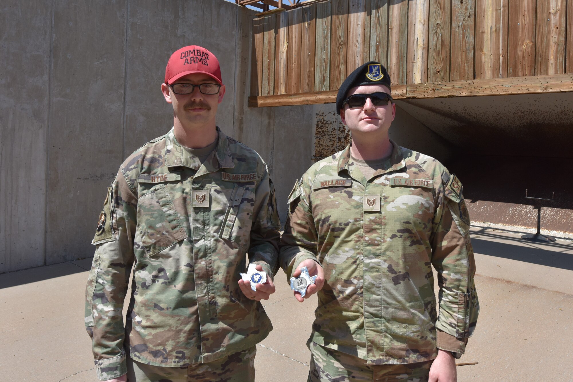 Two Airmen stand next to each other with coins in their hands