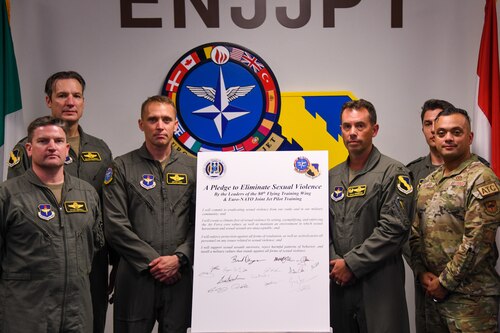 Members of the 80th Flying Training Wing and the Euro-NATO Joint Jet Pilot Training program stand together in front of the signed pledge canvas Aug. 28, 2023, at Sheppard Air Force Base, Texas. This joint pledge serves as a powerful testament to their dedication to supporting victims of sexual assault and their determination to eliminate such incidents from their ranks. (Courtesy Photo)