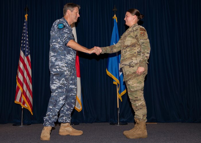 A military man shakes hands with a military woman.