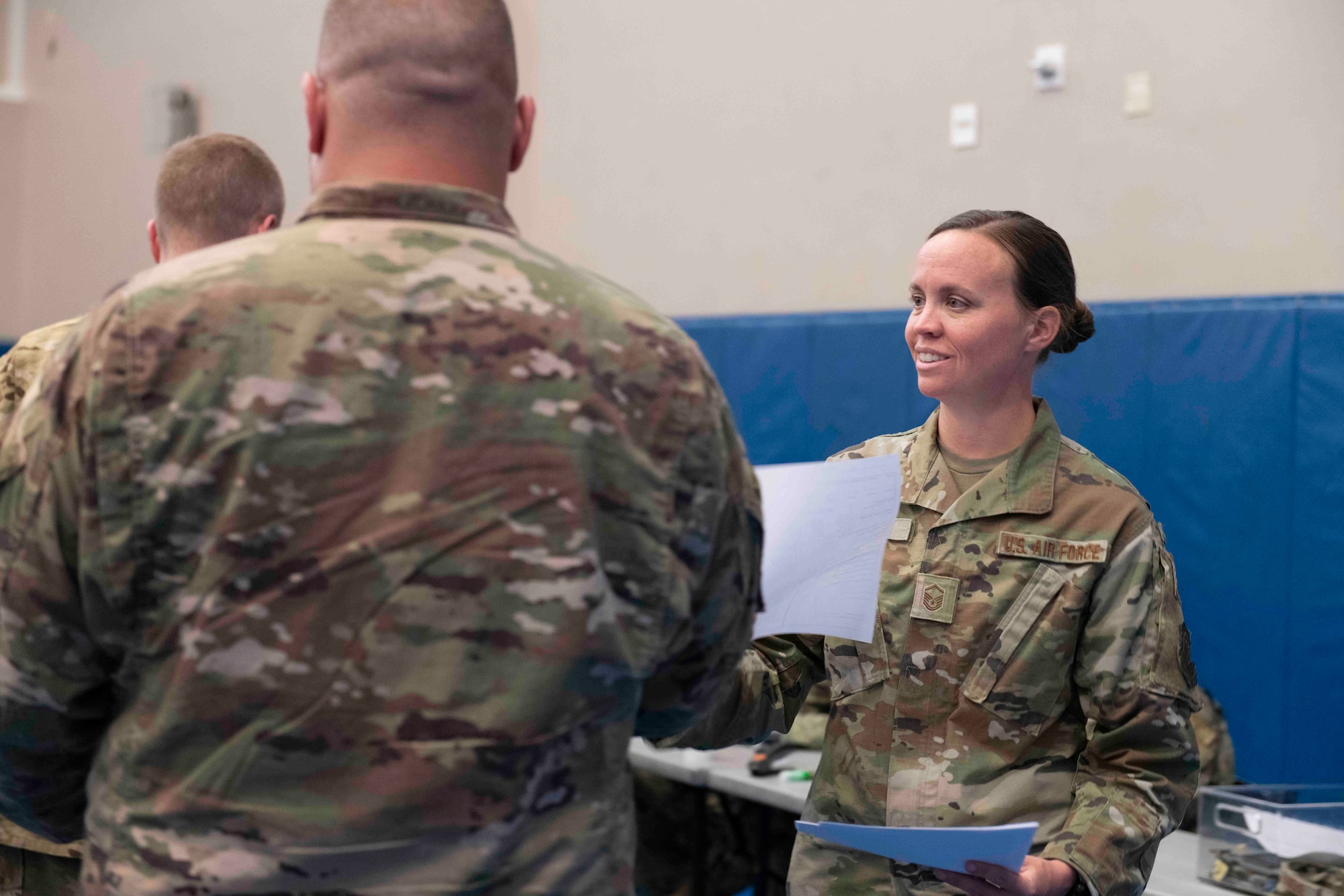 Photo of a woman handing a sheet of paper to a man