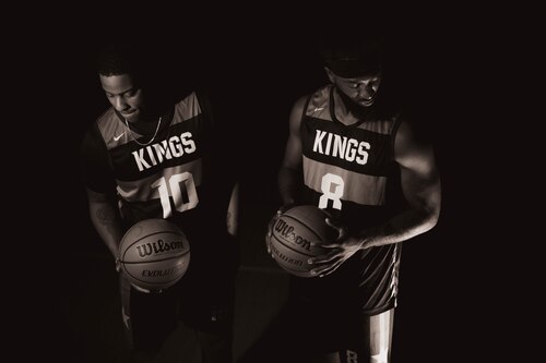 Two basketball players hold basketballs in a posed photo.