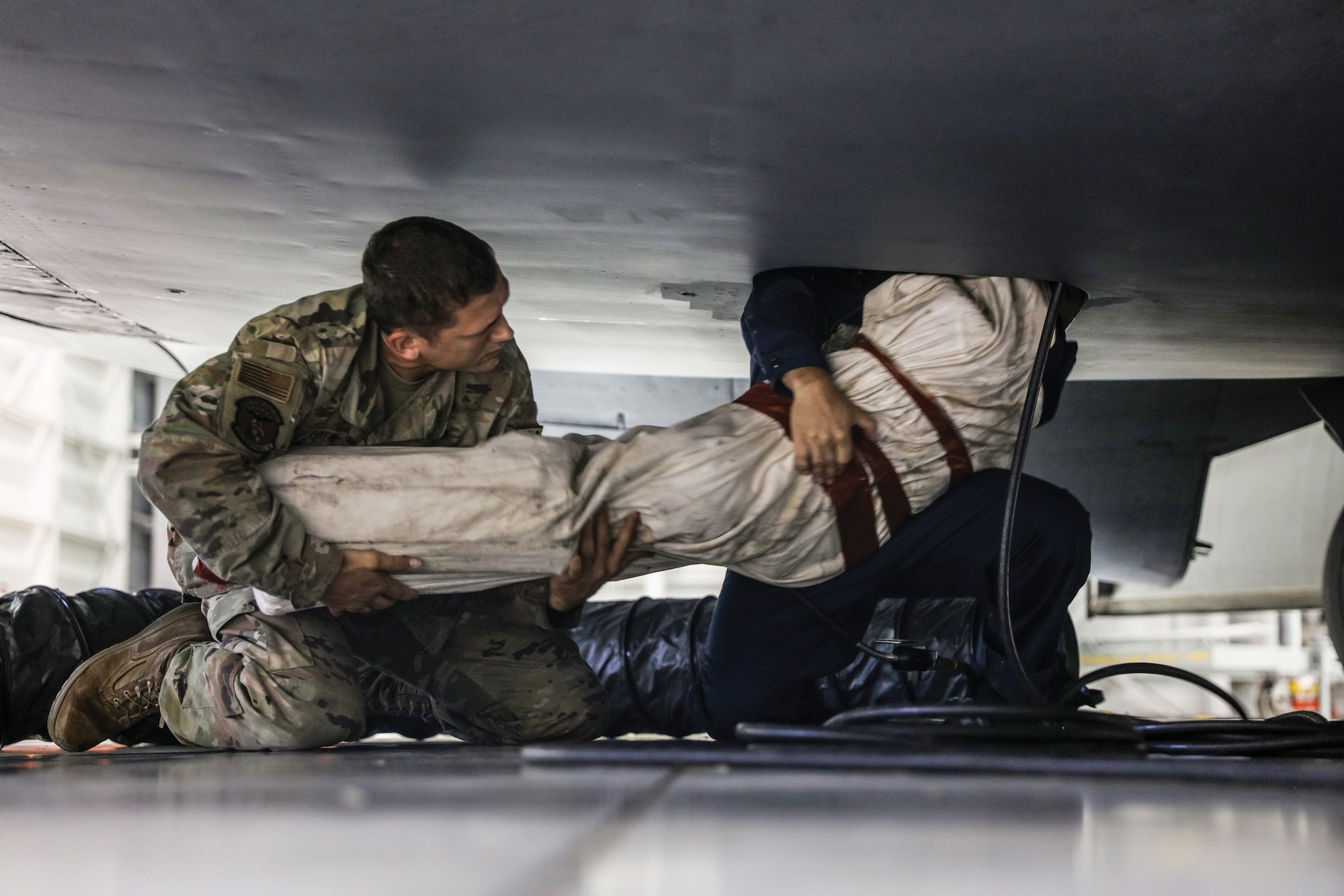 Tech. Sgt. Lucas Pickens, left, 445th Maintenance Squadron aircraft fuels systems craftsman, helps Senior Airman David Asterino, 445th MXS maintenance aircraft fuels systems journeyman, remove a training dummy used to simulate an unresponsive person from the aircraft underfloor maintenance tunnel of a C-17 Globemaster III during confined space training at Wright-Patterson Air Force Base, Ohio, Aug. 6, 2023. (U.S. Air Force photo by Master Sgt. Patrick O’Reilly)