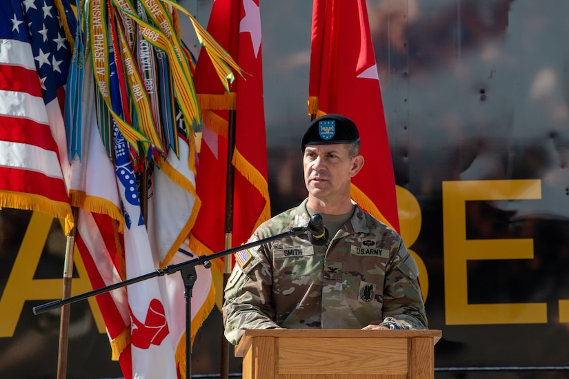 A male soldier stand behind a podium outside.