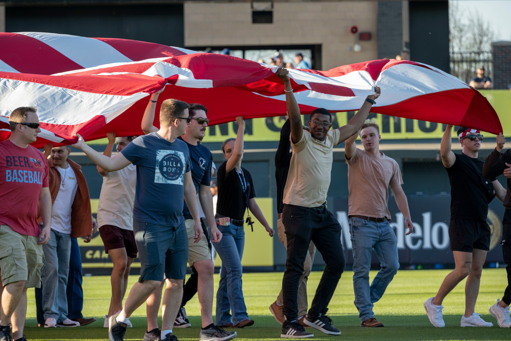 Airmen from McConnell Air Force Base, Kansas, and veterans carry an American flag onto the Riverfront Stadium baseball field for the national anthem April 11, 2023, in Wichita, Kansas. McConnell’s KC-46A Pegasus performed a flyover at the Wichita Wind Surge’s opening night. (U.S. Air Force Photo by Airman Gavin Hameed)