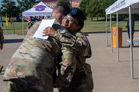 Two Army soldiers embrace in a hug.