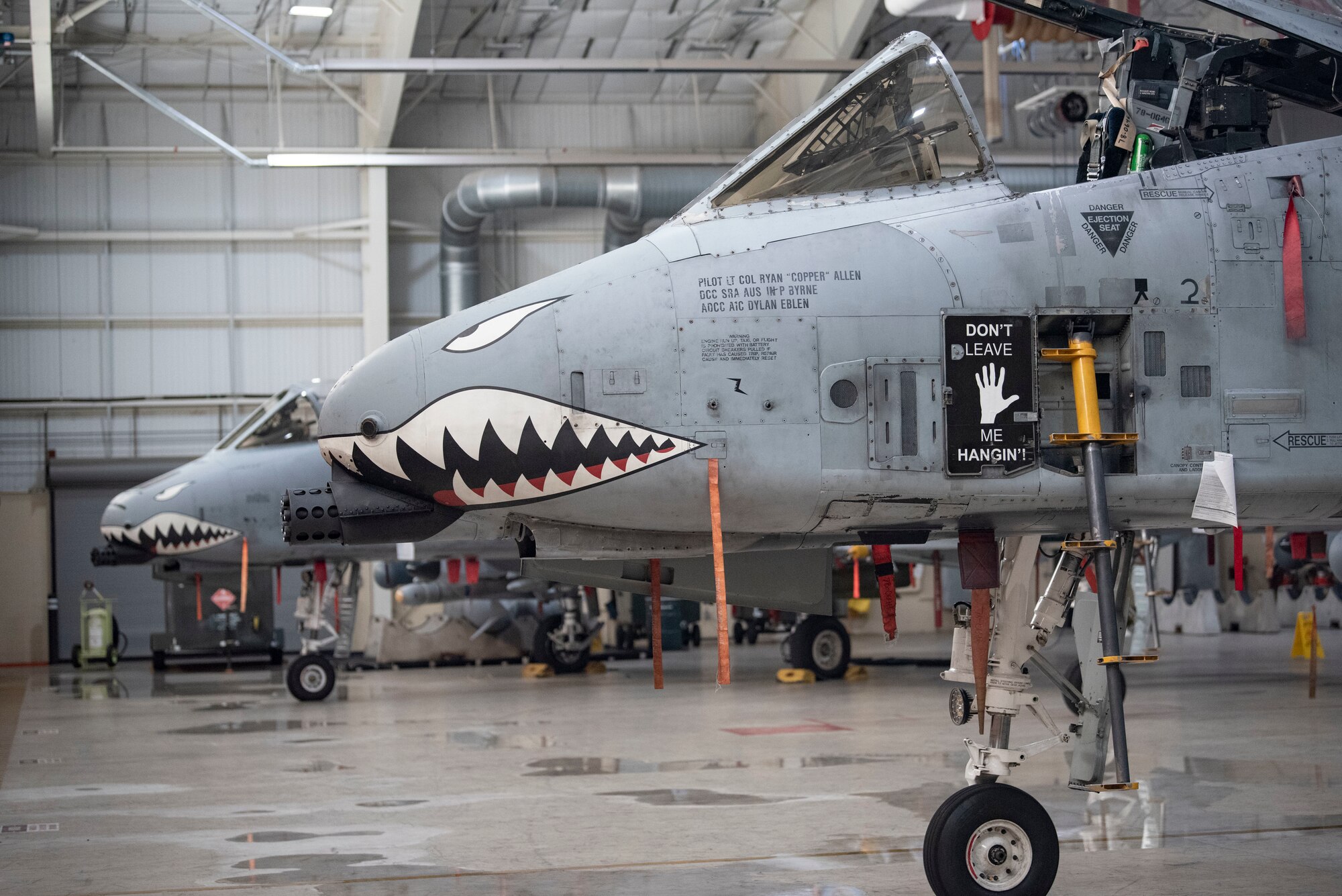 Two A-10C Thunderbolt II aircraft are parked in a hangar.