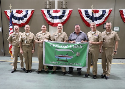 (Pictured left to right) Naval Surface Warfare Center, Philadelphia Division (NSWCPD) Constellation-class Frigate (FFG 62) Land Based Engineering Site (LBES) Program Representative Lt. Christopher Girouard, Deputy for Ships (OPNAV N96E) Capt. Warren Smith, PMS 515 FFG 62 Program Manager Capt. Andy Gold, U.S. Navy Program Executive Officer (PEO) for Unmanned and Small Combatants Capt. Kevin R. Smith, Doyon Industries Chief Operating Officer (COO) Anthony Woods, Naval Facilities Engineering Systems Command Mid-Atlantic (NAVFAC MIDLANT) Commanding Officer (CO) Capt. Matthew Riethmiller, and NSWCPD CO Capt. Joseph Darcy celebrate the Facility Overhaul Commencement Ceremony for the FFG 62 LBES in Philadelphia on Aug. 24, 2023. (U.S. Navy photo by Phillip Scaringi/Released)