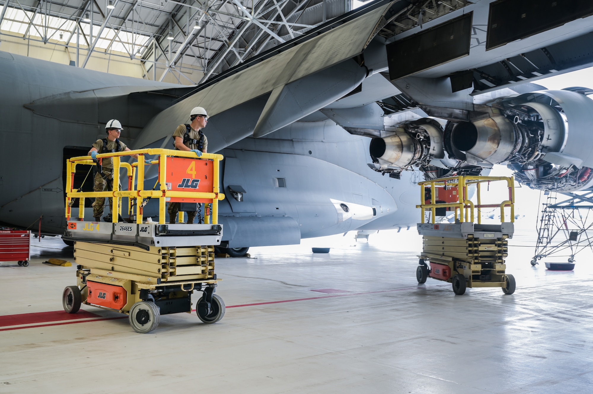 Airman 1st Class Jacob Pippin and A1C Michael Adair, 15th Maintenance Squadron crew chiefs, operate a motorized stand to inspect a C-17 Globemaster III during a home station check at Joint Base Pearl Harbor-Hickam, Hawaii, Aug. 7, 2023. Each C-17 undergoes a mandatory home station check every 180 days, allowing several maintenance shops to inspect the entire airframe and prolong its operational condition. (U.S. Air Force photo by Staff Sgt. Alan Ricker)