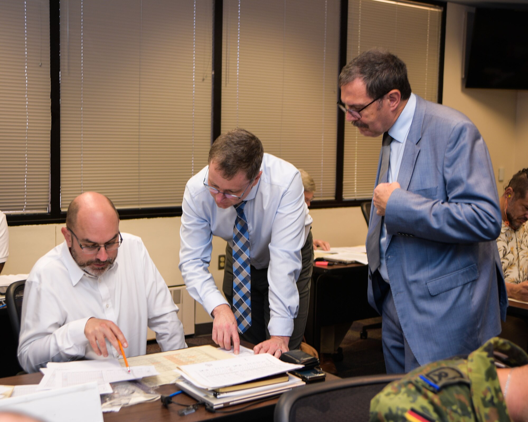 Instructors of the Allied Ammunition Storage and Transport Publication course help a student during a course application exercise, August 31, 2023. The week-long training focused on NATO standards for safe ammunition storage. (U.S. Air Force Photo by Ashley Palacios)