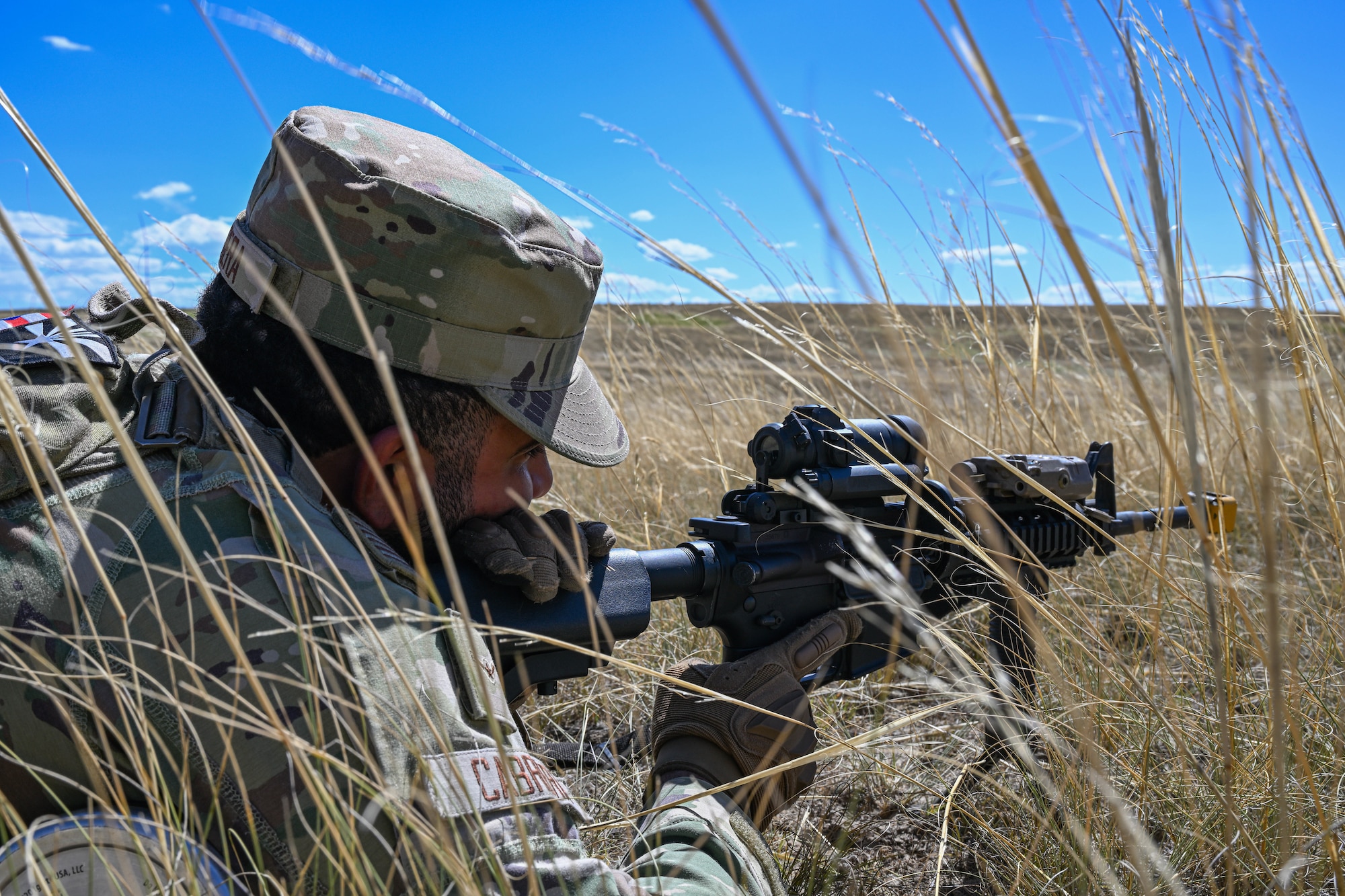 Airman Christopher Cabrera, 91st Missile Security Forces Squadron defender, aims his weapon during Operation Frontier Thunder at Camp Guernsey, Wyoming, Aug. 30, 2023. Cabrera provided overwatch security against simulated adversaries for his team while they traversed the landscape surrounding Camp Guernsey. (U.S. Air Force photo by Airman 1st Class Kyle Wilson)
