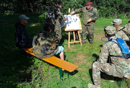 A member of the Association of Reservists of the German Armed Forces, Dülmen provides instruction to Capt. Roberto Rivera, Dülmen Army Prepositioned Stocks-2 worksite plans and operations officer, and Sgt. 1st Class Belloc Anim, the site’s senior supply noncommissioned officer, during the reserve unit’s annual comradeship bivouac, Aug. 26. (Courtesy photo)