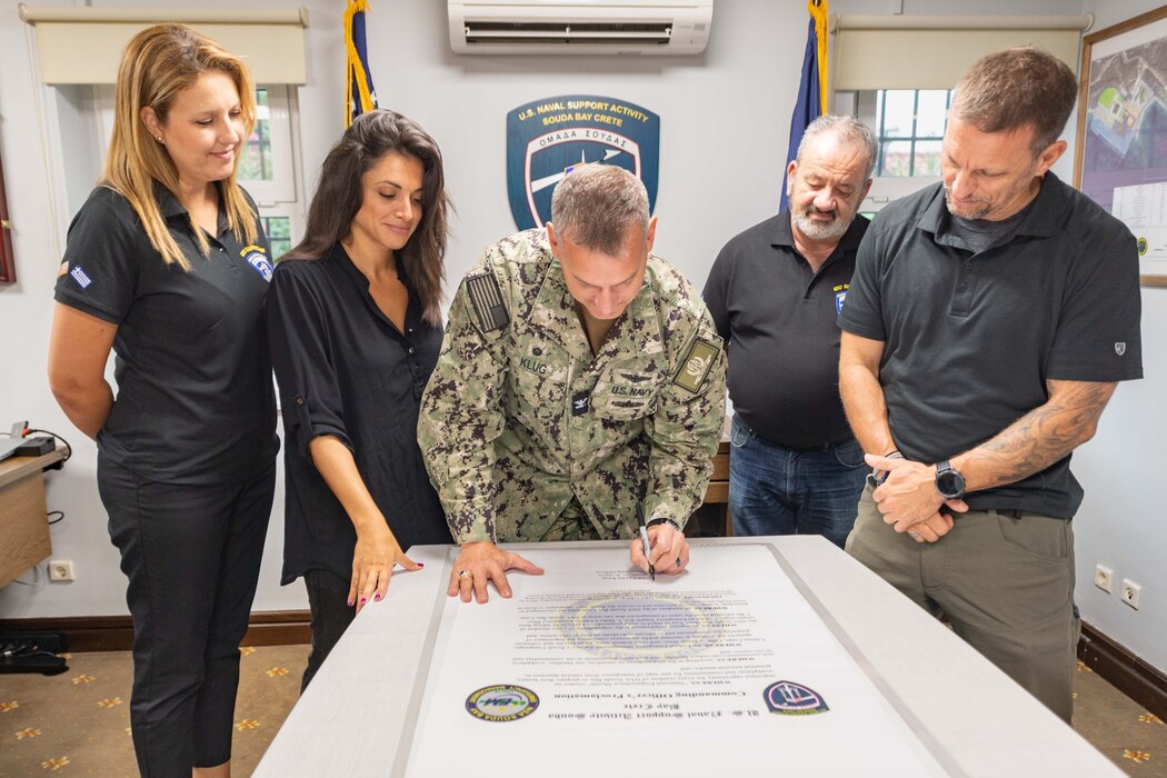 In recognition of National Preparedness Month, (from left) Eleni Skoulika, emergency dispatcher; Kyriaki Fragkioudaki, emergency dispatcher; Sam Kagadis, emergency dispatch supervisor; and Michael Tyburski, emergency management officer; all assigned to Naval Support Activity Souda Bay, Greece, observe as Capt. Odin J. Klug, commanding officer, NSA Souda Bay, signs a  proclamation confirming the installation’s commitment to emergency preparedness, Sept. 6, 2023.