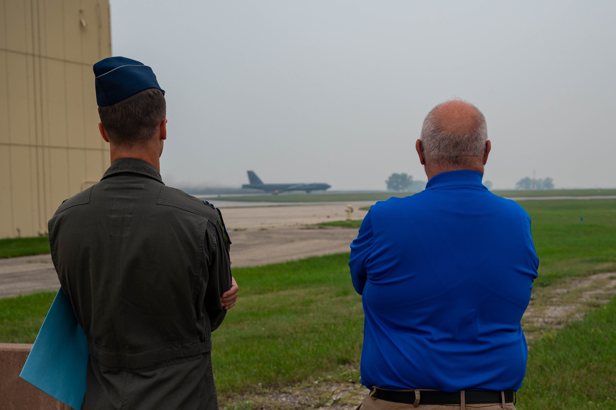 U.S. Air Force Capt. Levi Hilgenhold, 23rd Bomb Squadron B-52H Stratofortress pilot, and the Honorable Tom Ross, mayor of Minot, North Dakota, observe a B-52H Stratofortress taking off at Minot Air Force Base, North Dakota, Sept. 5, 2023. Mayor Ross was invited for an incentive flight and completed several ground training courses prior to his flight. (U.S. Air Force photo by Senior Airman Zachary Wright)