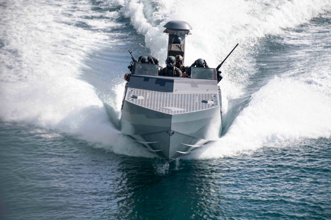 Service members travel in a boat through a body of water.