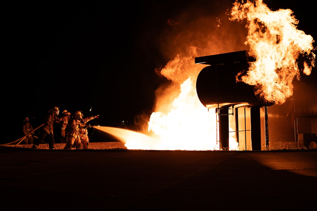 Marines use a water hose to fight a fire during training.