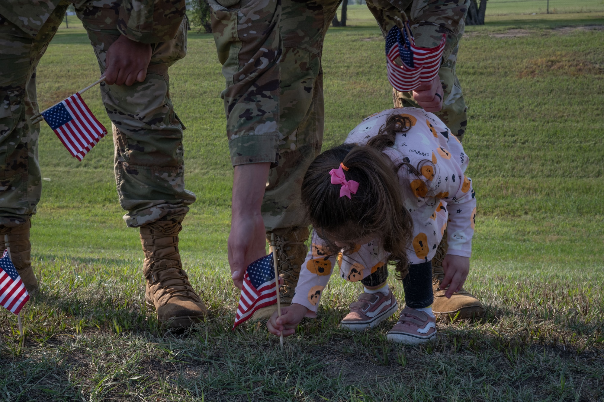 U.S. Air Force Staff Sgt. Richard Arias helps his daughter plant a flag at Minot Air Force Base, North Dakota, Sept. 6, 2023. The Airman volunteered for the third annual flag planting for Suicide Prevention Month. (U.S. Air Force photo by Airman 1st Class Trust Tate)