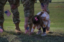 U.S. Air Force Staff Sgt. Richard Arias helps his daughter plant a flag at Minot Air Force Base, North Dakota, Sept. 6, 2023. The Airman volunteered for the third annual flag planting for Suicide Prevention Month. (U.S. Air Force photo by Airman 1st Class Trust Tate)