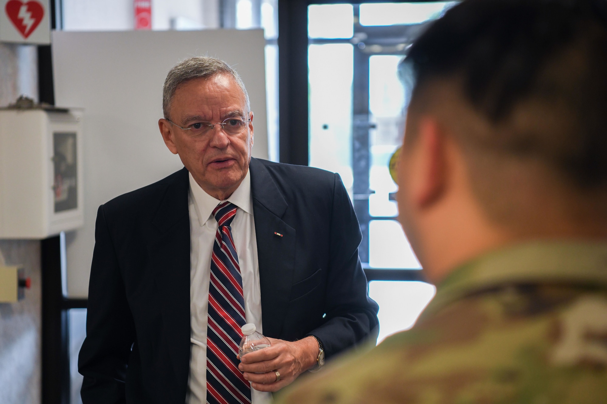 Man in suits talks to man in military uniform.