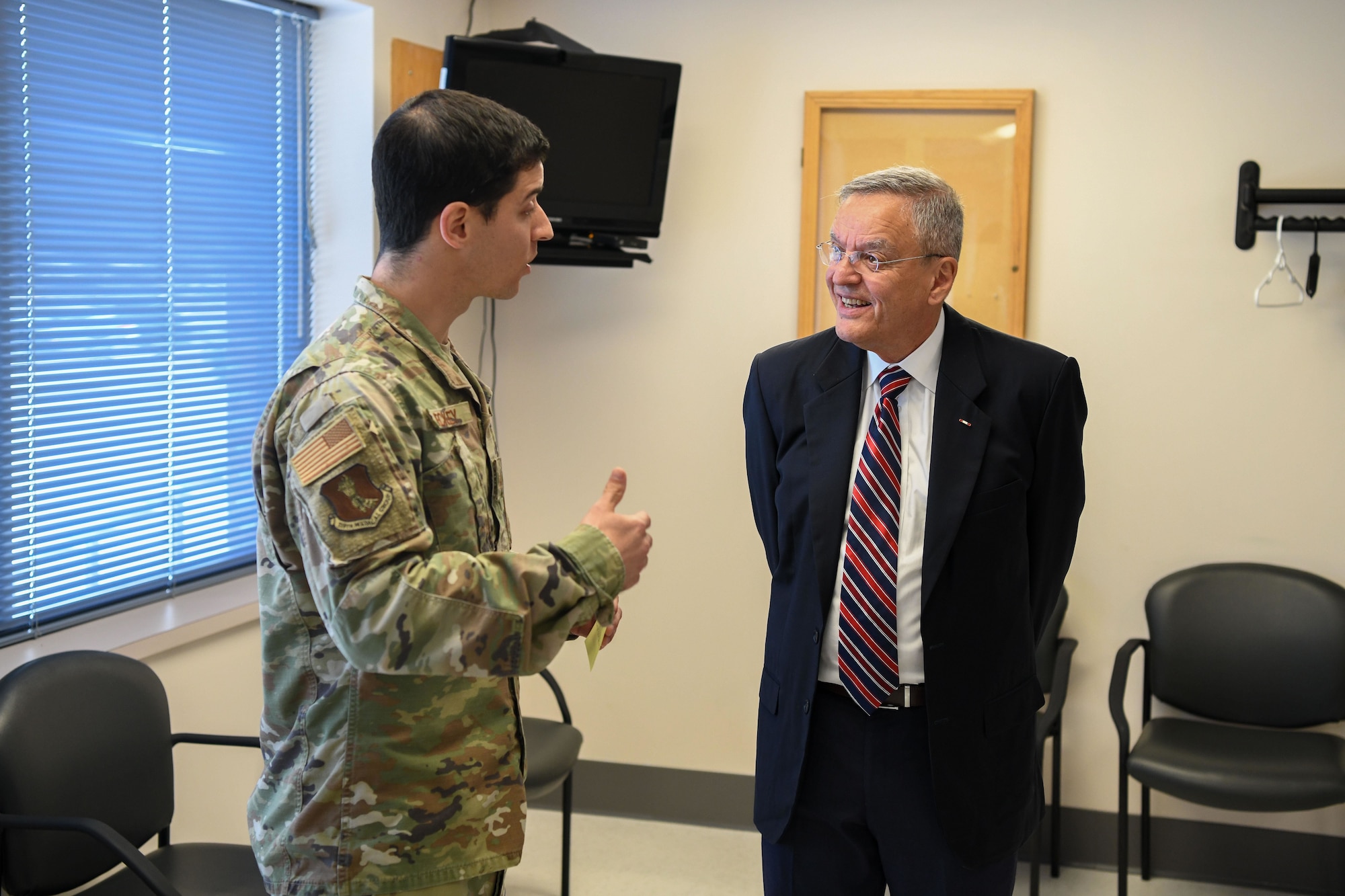 Man in suit talks to man in military uniform.