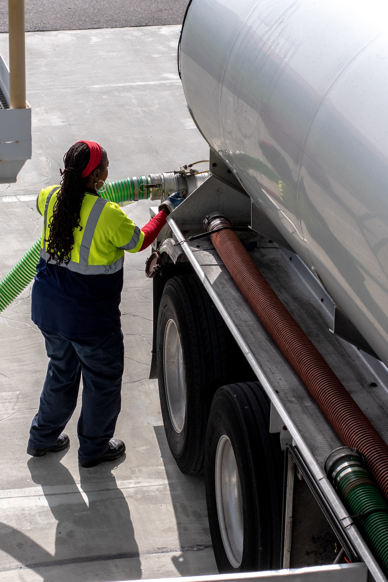 Yolanda Bush, Torrissi petroleum company transporter operator, connects an air vent hose to a fuel supply tanker truck at MacDill Air Force Base, Florida, August 22, 2023.