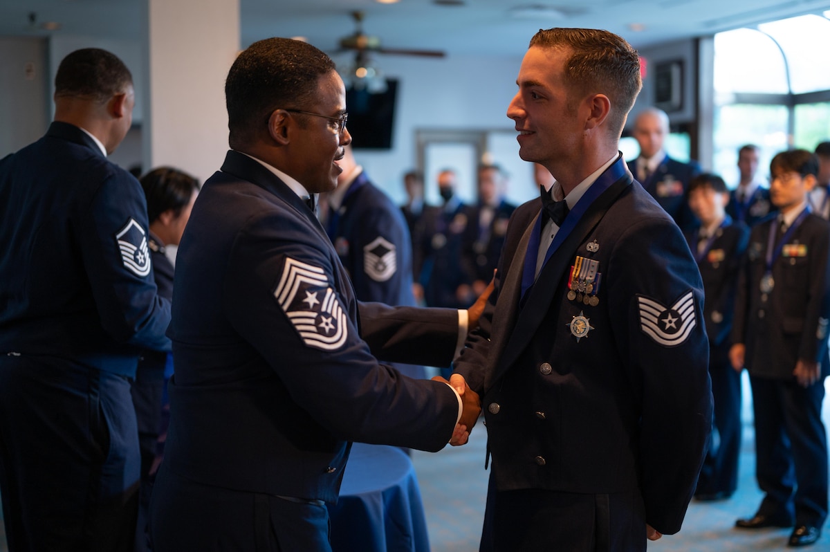 Chief Master Sgt. Jerry Dunn shakes hands with Tech. Sgt. Jacob Dunn at a an SNCO induction ceremony.