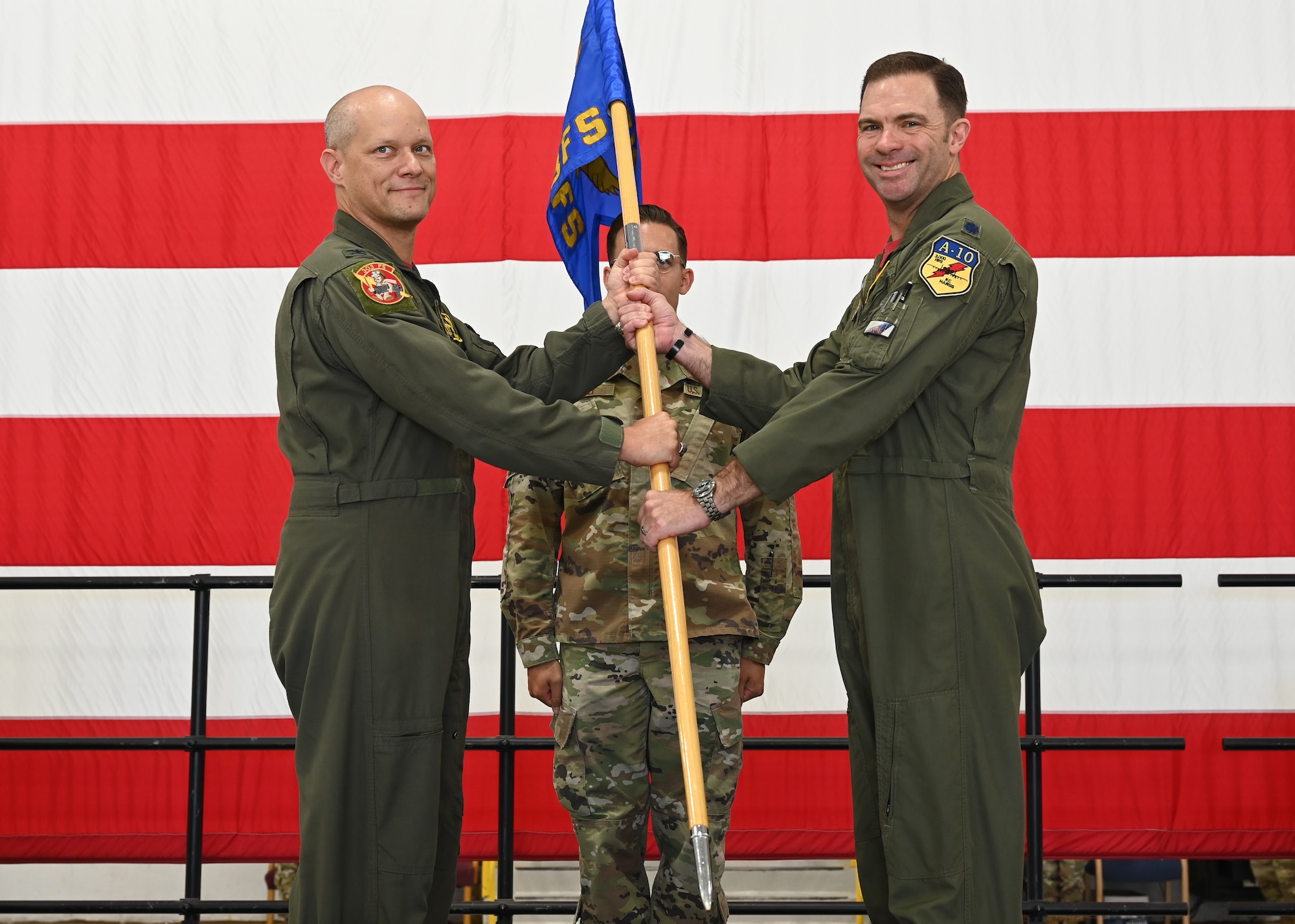 Two Air Force members hold a flag together.