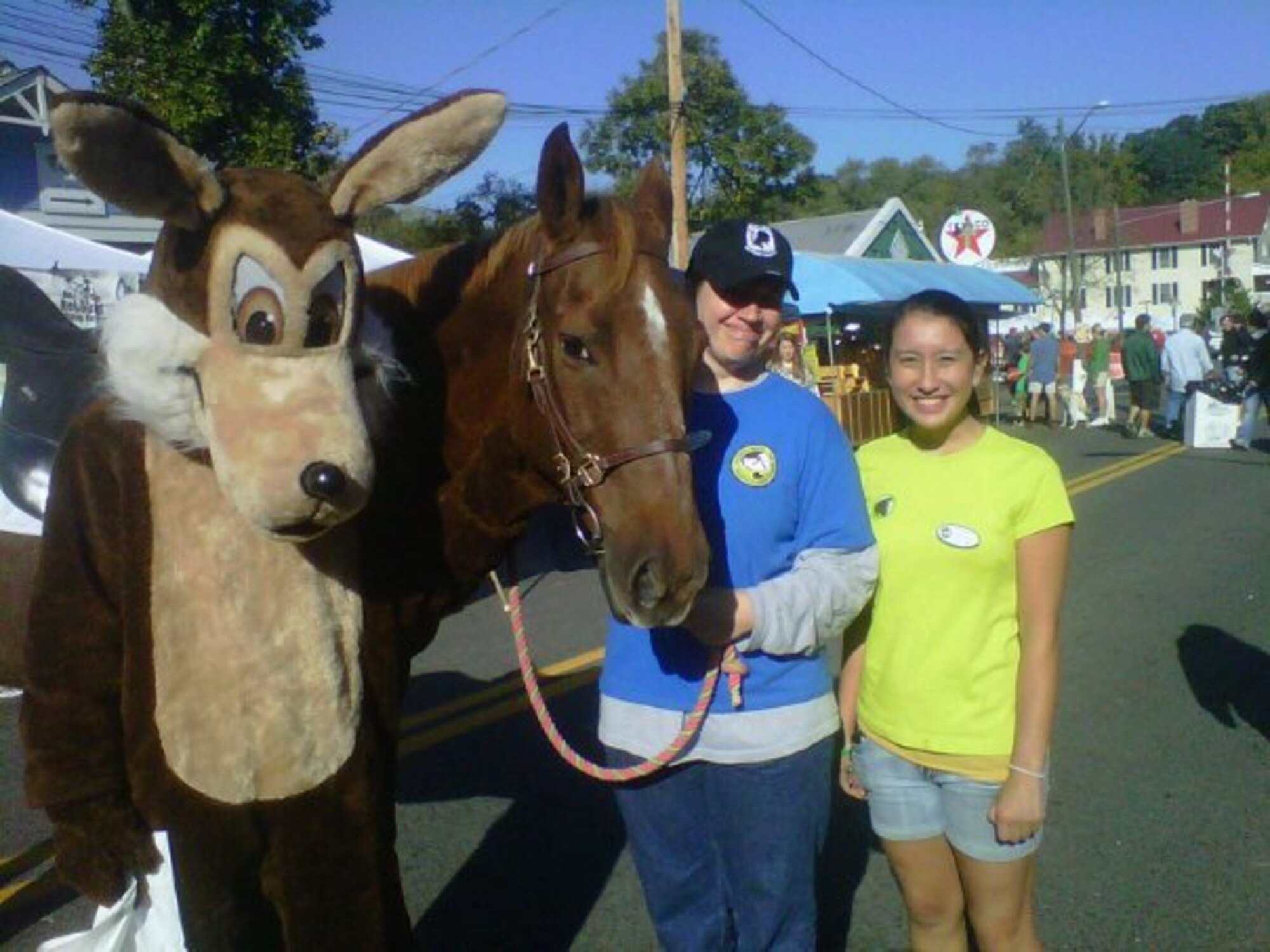Person in Wile E. Coyote costume poses next to horse and two females on a busy street