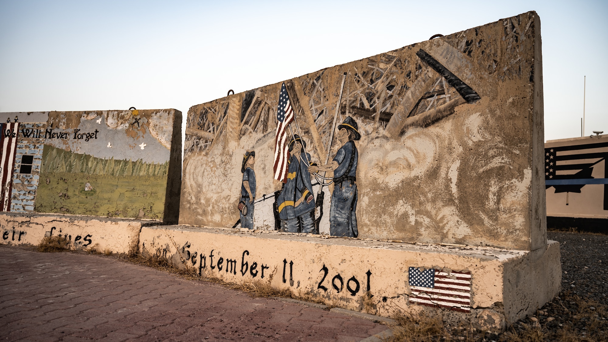 The 9/11 memorial display, weathered from the years under the desert sun, catches the sunrise at Ali Al Salem Air Base, Kuwait, Sept. 11, 2023. Service members from the U.S., Canada, Italy, and Denmark gathered together today for a moment of silence followed by a ruck march in remembrance of the innocent lives lost during the attacks on this fateful day 22 years ago. Sharing the past with our coalition partners secures a brighter future for us all. (U.S. Air Force photo by Staff Sgt. Kevin Long)