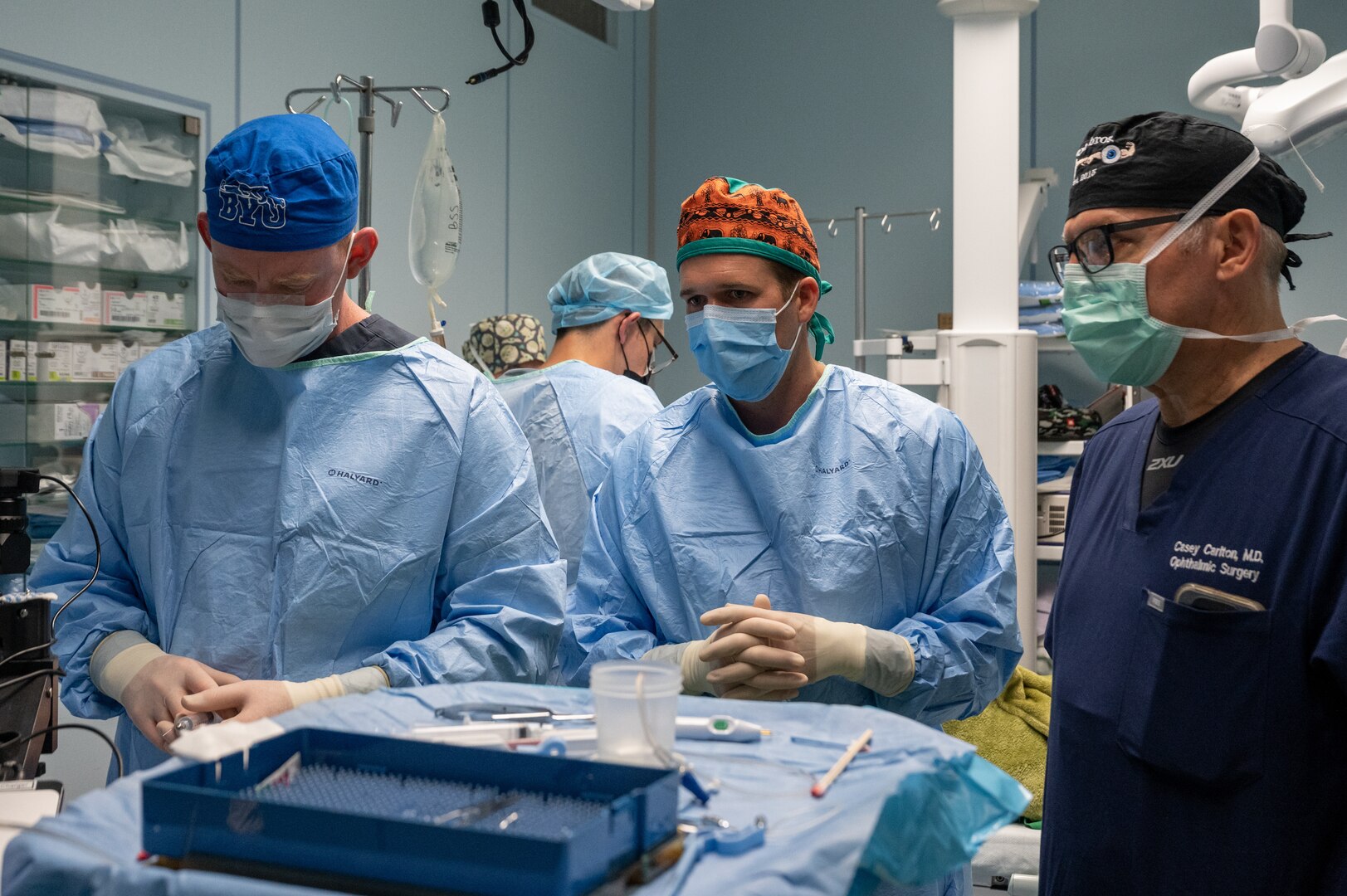 A team of ophthalmologists stand by a mayo stand full of medical instruments during a cataract surgery.
