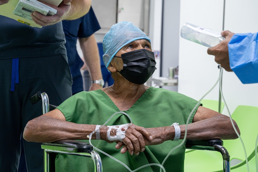 A patient sits in a wheelchair as he prepares to go to the operating room to receive cataract surgery.