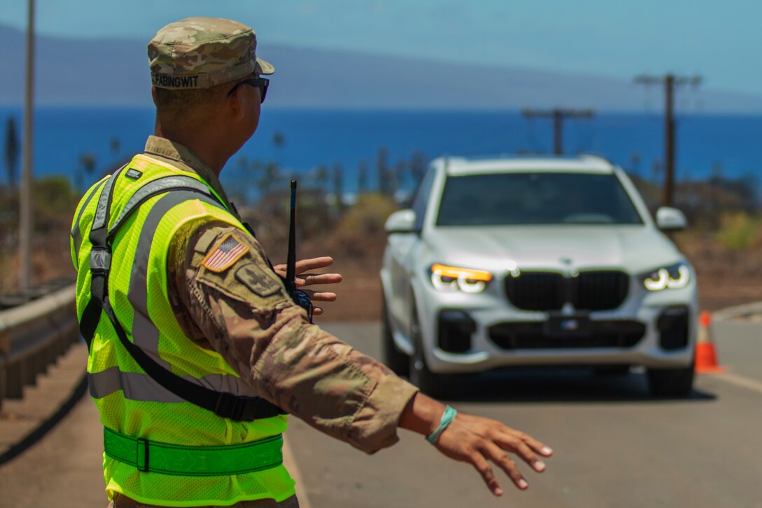 A soldier directs a civilian vehicle at an entry checkpoint.