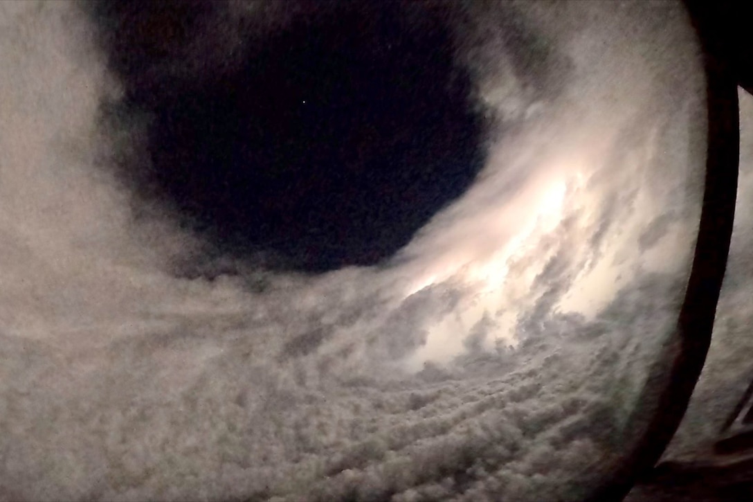 A nighttime view of the eye of a hurricane. The view is from the perspective of a military aircraft beneath the eye.