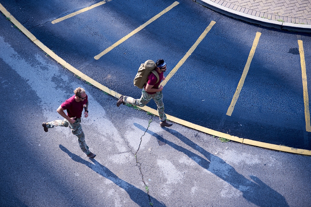 Overhead view of two service members running on asphalt.