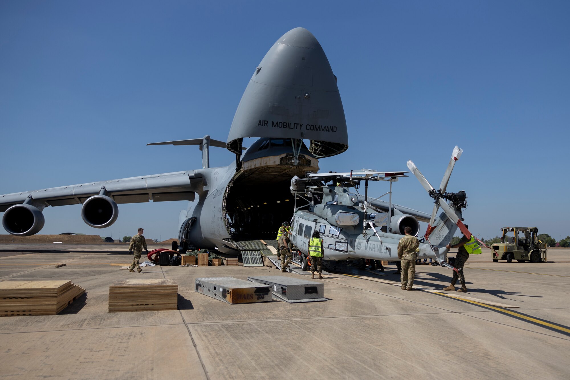 U.S. Marines with Marine Rotational Force – Darwin 23, U.S. Airmen, and Royal Australian Air Force Airmen offload an AH-1Z Viper helicopter with Marine Light Attack Helicopter Squadron 367 from a U.S. Air Force C-5M Super Galaxy with the 436th Airlift Wing at Royal Australian Air Force Base Darwin, Northern Territory, Australia, July 13, 2023. The C-5M transported U.S. Marine Corps attack helicopters to Darwin to allow forward air control in aerial and ground escort operations in order to maintain a crisis and contingency-ready force that can contribute to a free and open Indo-Pacific region. (U.S. Marine Corps photo by Cpl. Adeola Adetimehin)