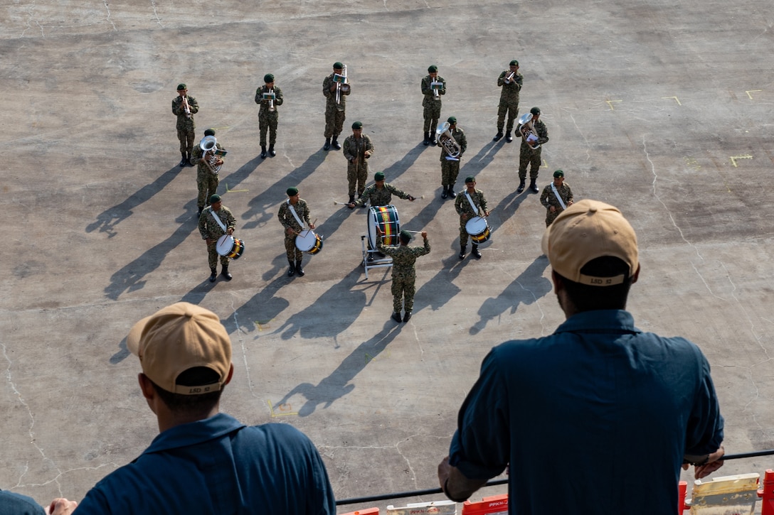 A group of musicians plays on a dock for an arriving ship.