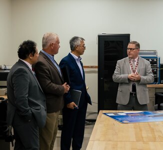 Four men talking in a classroom.