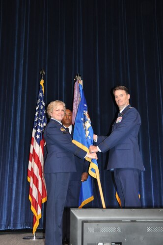 A person hands another person a flag