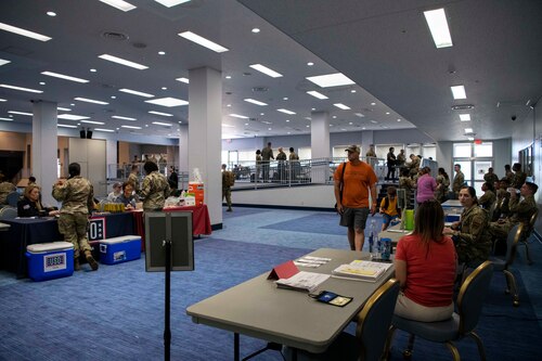A room set up with tables and people walking around.