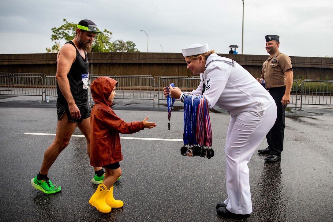 A sailor presents a medal to a young girl.