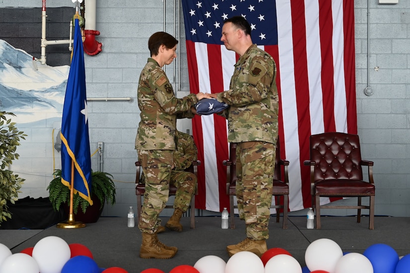Col. Lynn M. Lee, the incoming commander of the 111th Attack Wing, presents Col. Deane Thomey, the outgoing commander of the 111ATKW, with an American flag during an assumption of command ceremony at Biddle Air National Guard Base on Saturday, Sept. 9, 2023.