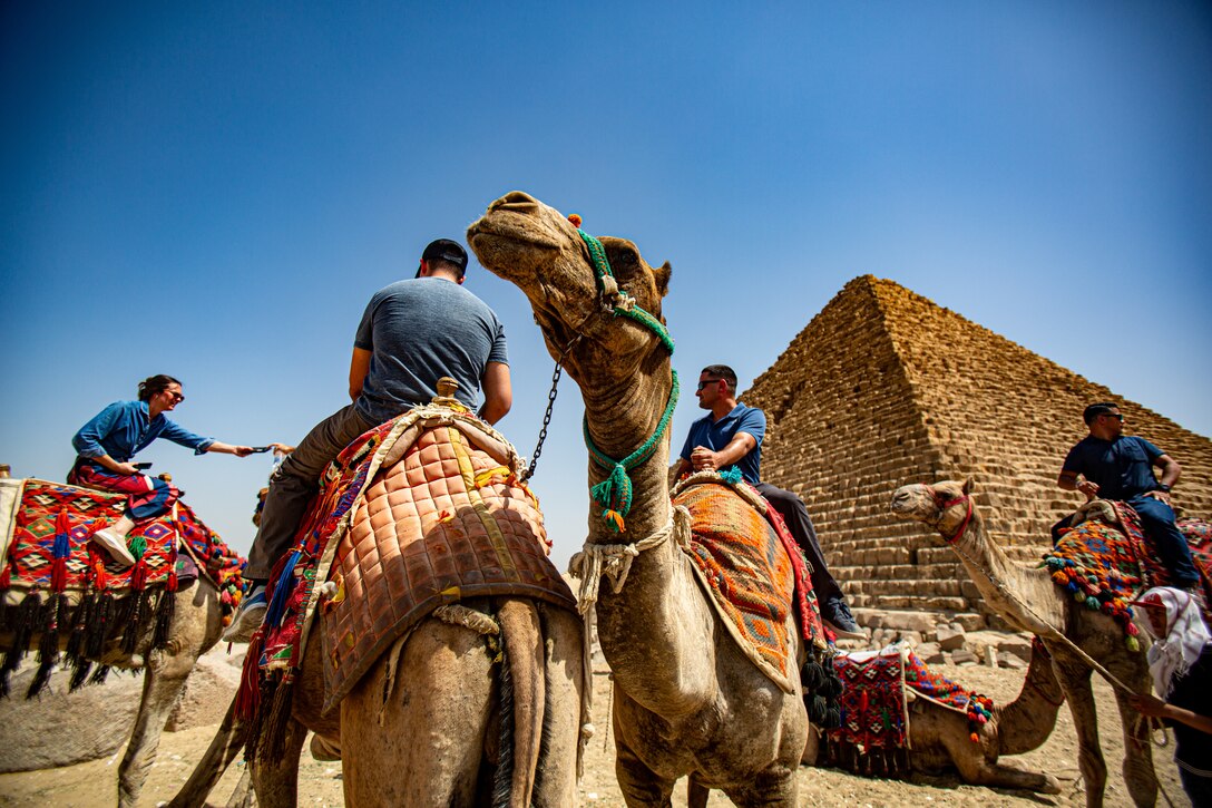 U.S. Marines with 1st Civil Affairs Group, Force Headquarters Group, Marine Forces Reserve ride camels around the pyramids on a tour for cultural day during exercise Bright Star 23 at Giza, Egypt, Sept. 8, 2023. Bright Star 23 is a multilateral U.S. Central Command exercise held with the Arab Republic of Egypt across air, land, and sea domains that promotes and enhances regional security and cooperation, and improves interoperability in irregular warfare against hybrid threat scenarios. (U.S. Marine Corps Photo by Capt. Mark Andries)