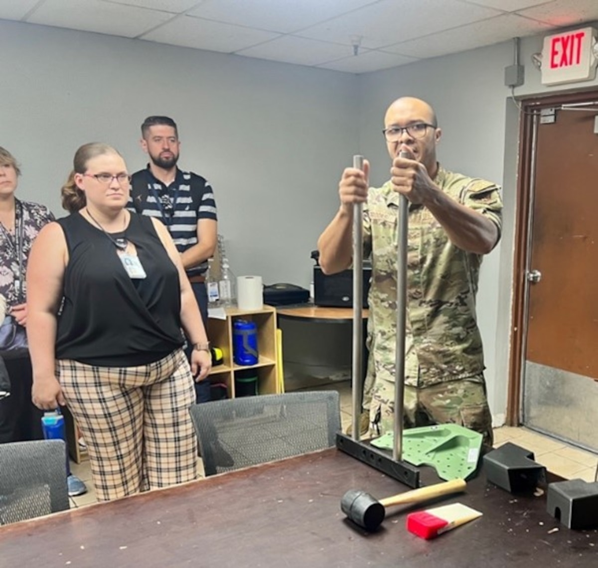 U.S. Air Force Tech. Sgt. Justin Brooks, right, 56th Component Maintenance Squadron aircraft fuel systems craftsman, demonstrates how the Spark Cell allowed his team to develop a time-saving tool to help maintain and repair aircrafts Aug. 8, 2023, as part of the annual Air Force Research Laboratory, or AFRL, Junior Force Council Bluing Trip at Luke Air Force Base, Ariz. Each year, AFRL hosts exploratory excursions to Air Force bases across the enterprise to expose military and civilian Airmen to missions and organizations outside of the employee’s regular operational duties. (U.S. Air Force photo / Kiara Palmer)