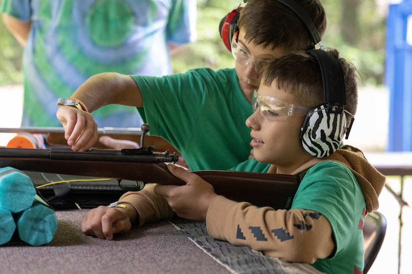 A camper inserts a bullet into another camper's .22-caliber rifle at the 2023 Kentucky National Guard Youth Camp.