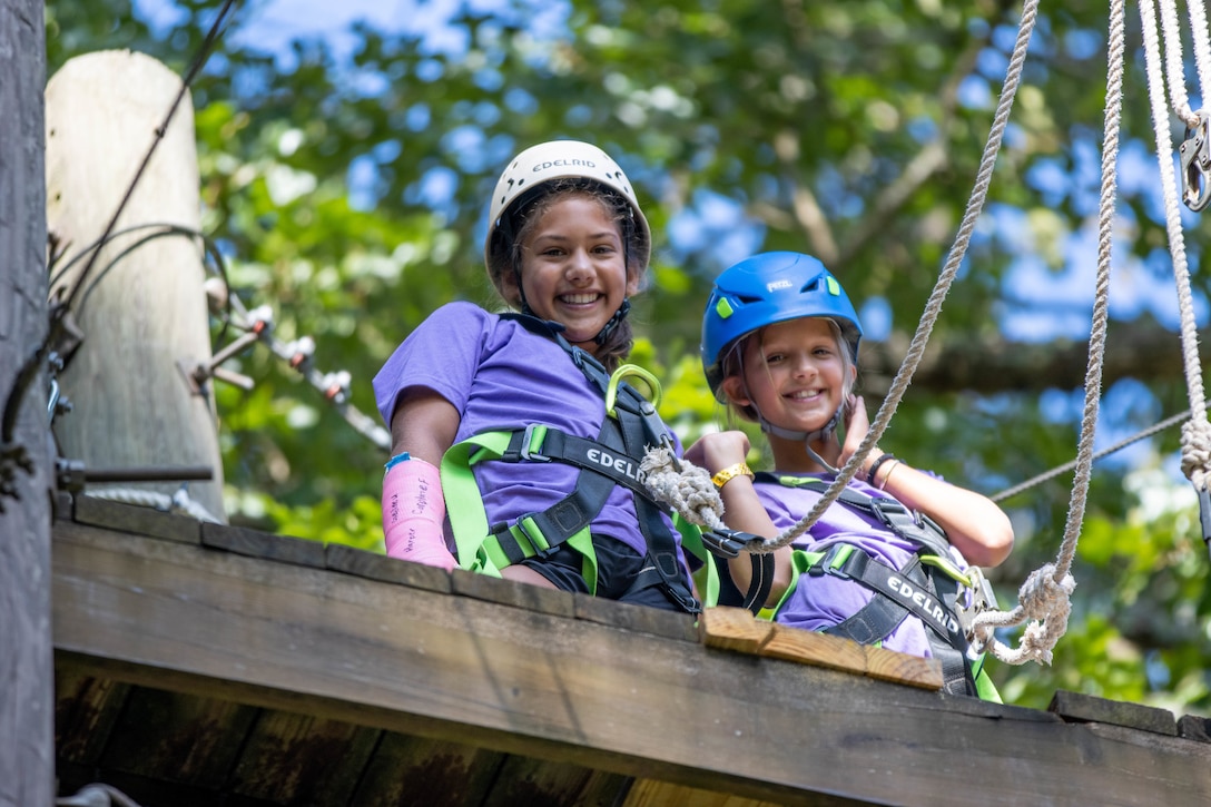 Two campers smile from the top of the climbing tower at the 2023 Kentucky National Guard Youth Camp.
