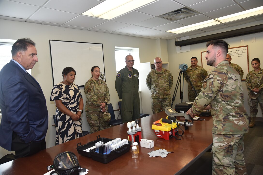 People in military uniforms and civilian clothes talk around a table.